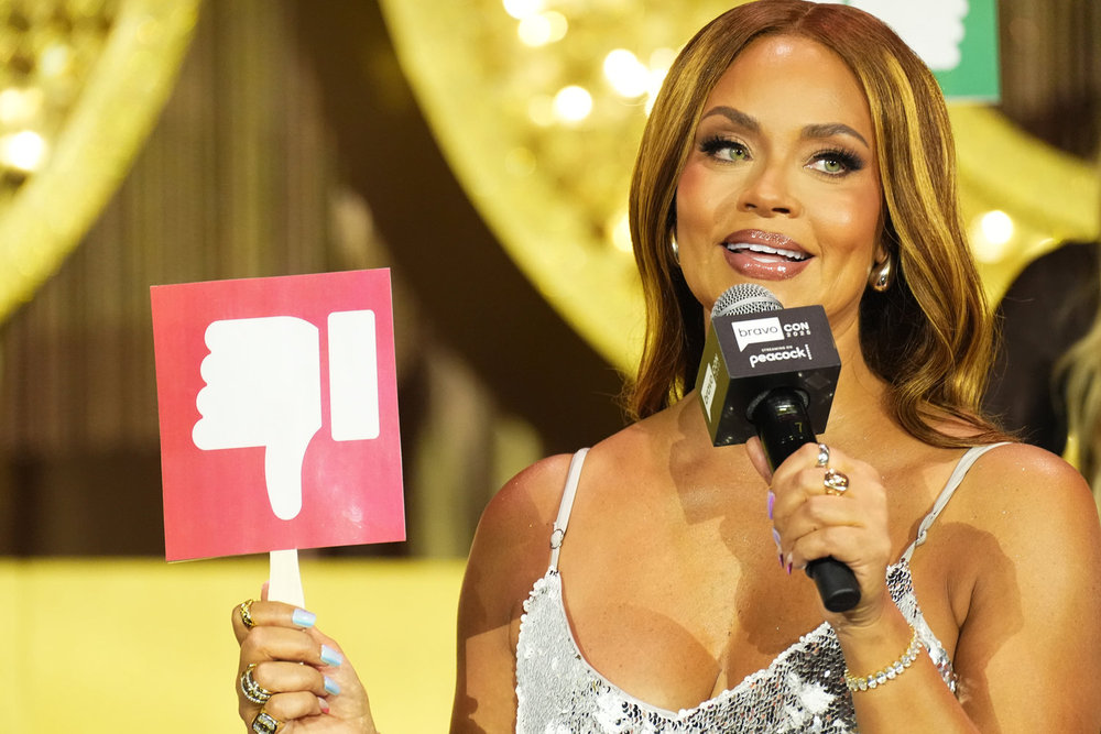 Gizelle Bryant à BravoCon tenant une pancarte avec un pouce vers le bas 